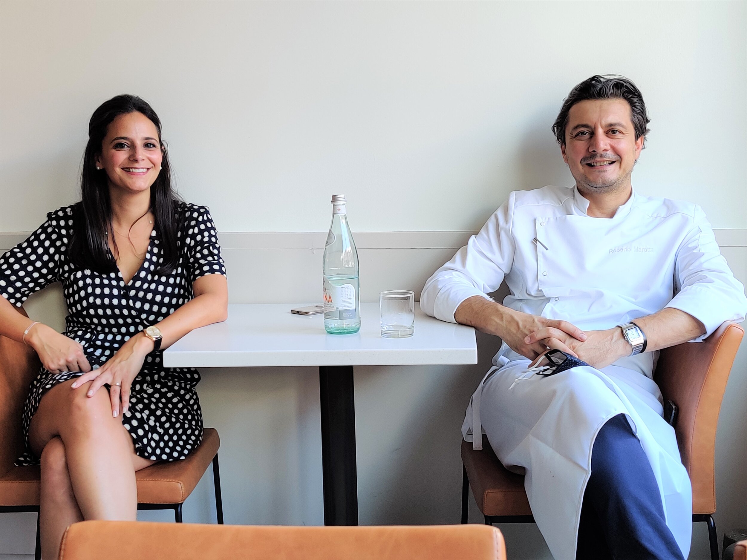 Roberto and Jacqueline sitting side by side at a table, facing the camera, and smiling