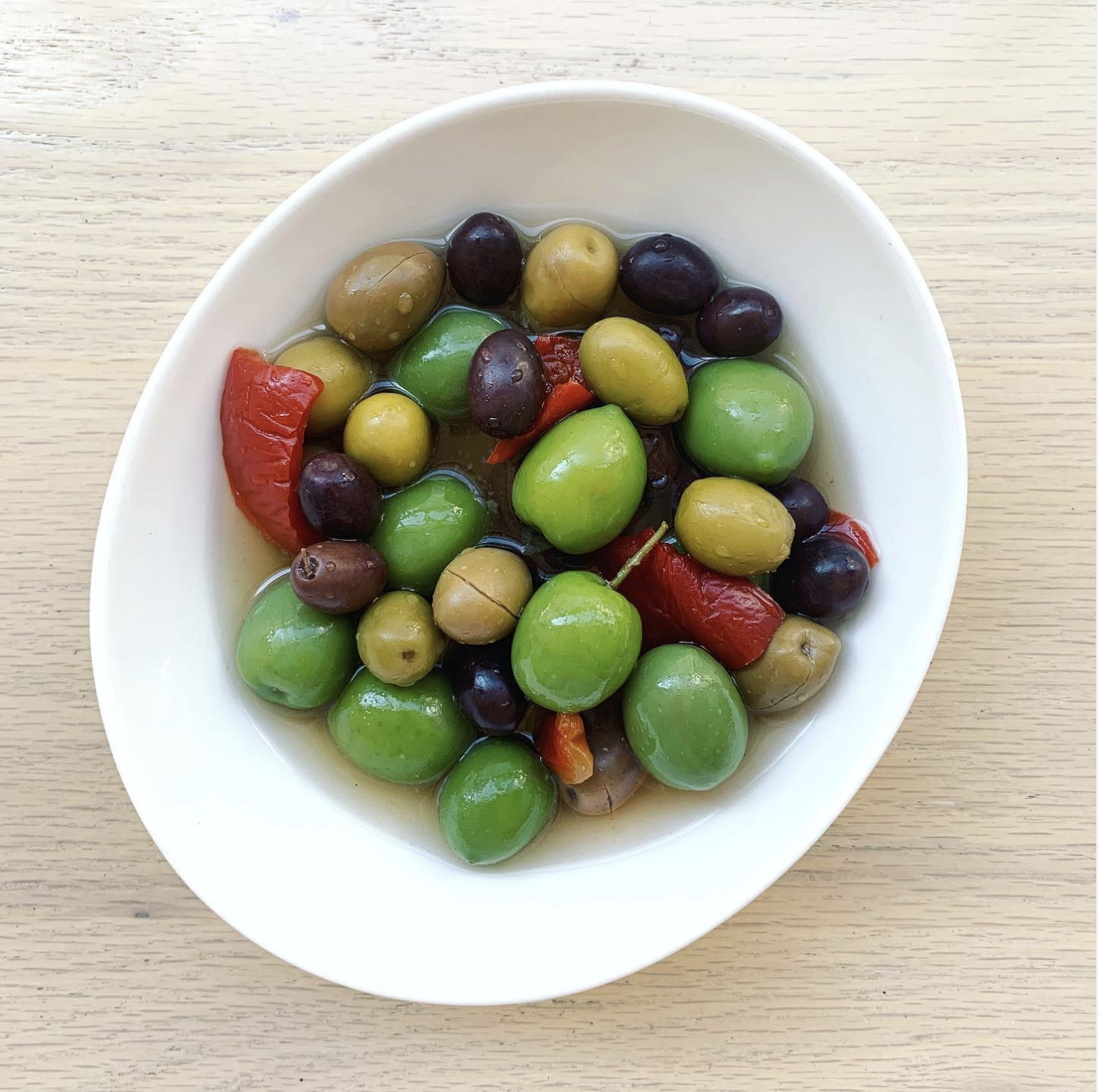 Multi-coloured olives in a bowl with red peppers